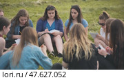 A group of female students are sitting in a circle on a meadow for collective work with notebooks. Стоковое видео, видеограф Mikhail Davidovich / Фотобанк Лори