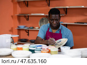 Man potter painting new ceramic plate. Стоковое фото, фотограф Яков Филимонов / Фотобанк Лори