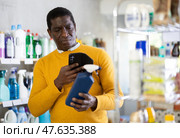 African man buyer scan QR code on packaging of spray in shop. Стоковое фото, фотограф Яков Филимонов / Фотобанк Лори