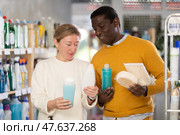 During shopping, African male client with wife advised and choose shampoo, shower gel, bast wisp. Стоковое фото, фотограф Яков Филимонов / Фотобанк Лори