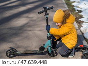 A little boy in bright yellow clothes rides a scooter. A happy child walks outside in early spring. Happy childhood. Стоковое фото, фотограф Photojuli / Фотобанк Лори
