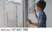 A boy draws on a window, showing creativity and curiosity about the world. Стоковое видео, видеограф Cantemir Dumitru / Фотобанк Лори