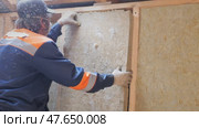 Insulation of a frame house with mineral wool. Cutting, fitting, laying insulation. Construction works. Стоковое видео, видеограф Константин Мерцалов / Фотобанк Лори