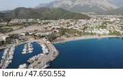 Picturesque summer aerial view of coastal area of Kemer and marina with moored yachts on Mediterranean coast on background of Taurus Mountain range, Antalya province. Famous resort on Turkish Riviera. Стоковое видео, видеограф Яков Филимонов / Фотобанк Лори