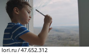 A boy creatively plays, drawing on a window, then brushes his teeth. Стоковое видео, видеограф Cantemir Dumitru / Фотобанк Лори