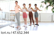Group of enthusiastic young female ballet students focused on mastering graceful Demi rond de jambe par terre exercise at barre in mirrored well-lit choreography studio. Стоковое видео, видеограф Яков Филимонов / Фотобанк Лори