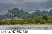 Beautiful mountains against the sky and clouds. Green vegetation on the slopes and in the valley. The river is in the foreground. China. Li River. Li Jiang. Guilin. Стоковое фото, фотограф Вера Ивановна Кубарева / Фотобанк Лори