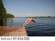 Athletic woman in swimsuit diving headfirst from a pier into the lake. Sunny summer day, dynamic outdoor action. Стоковое фото, фотограф Скоробогатова Е. / Фотобанк Лори