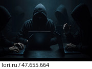 Хакеры. Мужчина в балаклаве держит смартфон и кредитную карту в тёмной обстановке. Стоковое AI-изображение, AI-художник Башкирова Анна / Фотобанк Лори