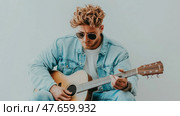 Musical Serenade: A Man in Denim Plays an Acoustic Guitar. Стоковое AI-изображение, AI-художник Данила Большаков / Фотобанк Лори
