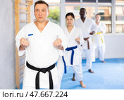 Women and men in kimono in fight stance during group karate training. Стоковое фото, фотограф Яков Филимонов / Фотобанк Лори