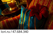 Interior Stilllife: Sumptuous armchair adorned with velvet cushion and vibrant red flower, lit by golden lamp for Luxurious Home Decor. Стоковое AI-изображение, AI-художник Данила Большаков / Фотобанк Лори