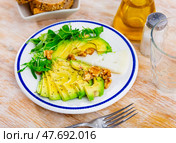 On table there is plate with snack - pieces of avocado pulp, walnut and arugula. Стоковое фото, фотограф Яков Филимонов / Фотобанк Лори
