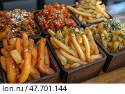 Delicious variety of fries displayed in paper bags at a food location. Красочное ассорти картофеля фри представлено в бумажных пакетах: сладкий картофель фри, кудрявый картофель фри и классический золотистый картофель фри. Идеально подходит для любителей перекусить в заведениях повседневного питания. Стоковое AI-изображение, AI-художник Katsiaryna Repich / Фотобанк Лори