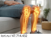 A man sits on a sofa with his hand on his knee, and through his legs are visualized glowing anatomical bones of the lower limbs - the hip, knee and ankle joints. Digital illumination of the bone structure emphasizes the medical or orthopedic theme of the image, ideal for articles and resources related to joint treatment, diagnostics, orthopedics, traumatology and physical therapy. Стоковое AI-изображение, AI-художник Анна Кривицкая / Фотобанк Лори