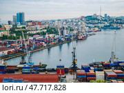 Vladivostok, Russia - August 9, 2021: Cargo cranes loading colorful containers in the port of vladivostok, russia, with the zolotoy rog bridge in the background. Редакционное фото, фотограф Mikhail Davidovich / Фотобанк Лори
