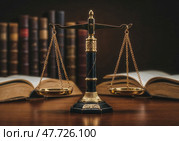 На строгом столе стоят весы Фемиды, символизируя справедливость и правопорядок. Вокруг видны книги с юридическими текстами, создавая атмосферу правосудия. Стоковое AI-изображение, AI-художник Сергей Никифоров-Гордеев / Фотобанк Лори