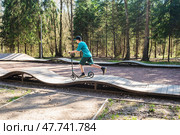 12-летний мальчик в кепке и шортах катается на самокате на памп-треке в Боровском парке в Москве весной. Стоковое фото, фотограф Яна Проничева / Фотобанк Лори
