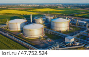 Вид с воздуха на промышленные резервуары для переработки биогаза среди пышных зеленых полей в лучах золотого солнца. Стоковое AI-видео, аниматор ФотоИнтеллект / Фотобанк Лори