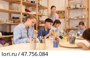 Interested children of different ages painting ceramic objects with teacher in art studio. Стоковое видео, видеограф Яков Филимонов / Фотобанк Лори