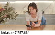 Portrait of upset frustrated young woman standing in home kitchen, looking at smartphone, waiting for message. Стоковое видео, видеограф Яков Филимонов / Фотобанк Лори