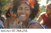 A woman with a vibrant headband smiles brightly while attending an outdoor music festival, with blurred festival-goers in the background. Стоковое AI-изображение, AI-художник Данила Большаков / Фотобанк Лори