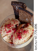 Borodino bread flavored ice cream scoops garnished with rye crisps, dried raspberries, resting in glass dessert bowl on rustic surface. Стоковое фото, фотограф Данил Руденко / Фотобанк Лори