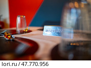 Metal reserved sign placed on elegantly set restaurant table, indicating designated dining space with polished silverware and crystal glassware waiting for incoming diners. Стоковое фото, фотограф Данил Руденко / Фотобанк Лори