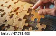 A person placing a puzzle piece onto a larger puzzle, concentrating on fitting it perfectly. Стоковое AI-изображение, AI-художник Данила Большаков / Фотобанк Лори
