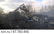 Crane lifting debris at a scrapyard during daylight cleanup operation with firefighters present. Стоковое фото, фотограф Александра Рублева / Фотобанк Лори