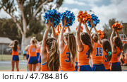 A group of girls dressed in orange and blue cheerleading uniforms, energetically performing cheers and synchronized routines at a sporting event. Стоковое AI-изображение, AI-художник Данила Большаков / Фотобанк Лори