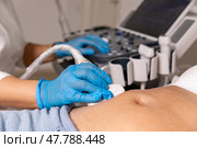 In the hospital, close-up shot of the doctor does ultrasound sonogram procedure to a pregnant woman. Obstetrician moving transducer on the belly of the future mother. High quality photo. Стоковое фото, фотограф Ирина Михайличенко / Фотобанк Лори