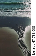 Sunlight gleaming on wet shoreline, stream merging with ocean waves, creating sparkling coastal landscape at golden hour. Стоковое видео, видеограф ILIA GOROKHOV / Фотобанк Лори
