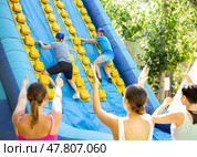 Cheerful man climbing on inflatable slide with wooden poles. Стоковое фото, фотограф Яков Филимонов / Фотобанк Лори