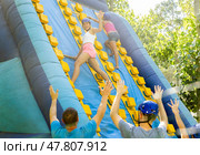 Cheerful girl climbing on inflatable slide with wooden poles. Стоковое фото, фотограф Яков Филимонов / Фотобанк Лори