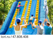Young women competing in climbing with wood poles on inflatable slide. Стоковое фото, фотограф Яков Филимонов / Фотобанк Лори