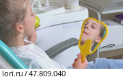 Little girl are eating green apple in the dentist's chair and looking in the mirror at her teeth. Healthy teeth concept. Child eat a green apple. Slow motion footage. Стоковое видео, видеограф Ирина Михайличенко / Фотобанк Лори
