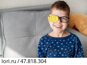 Portrait of little boy wearing glasses with occluder to correct vision sitting on sofa at home. Стоковое фото, фотограф Кашапова Эльвира / Фотобанк Лори