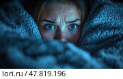The young woman looks frightened, her expressive blue eyes wide with dread as she cuddles into a soft blanket while watching a thrilling show. Стоковое AI-изображение, AI-художник Данила Большаков / Фотобанк Лори