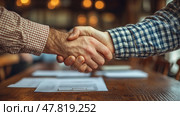 A confident handshake symbolizes agreement and partnership between two individuals in a warm café setting. Стоковое AI-изображение, AI-художник Данила Большаков / Фотобанк Лори