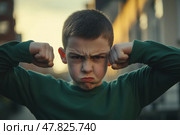 Angry furious little child boy looking at the camera outdoors at the city street. Unhappy grumpy boy showing his biceps. Provocation. Kid boy shows his muscles. Elementary school problems. Bullying. Стоковое AI-изображение, AI-художник Марина Демидюк / Фотобанк Лори