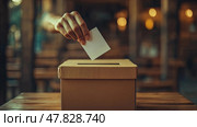 A hand places a ballot into a cardboard box, symbolizing civic duty and participation in the electoral process at a local polling location. Стоковое AI-изображение, AI-художник Данила Большаков / Фотобанк Лори