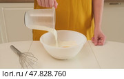 Person pouring milk from measuring jug into bowl with flour. Studio kitchen scene. Dough making process and baking ingredient concept. Close-up shot. Стоковое видео, видеограф Андрей Журавлев / Фотобанк Лори