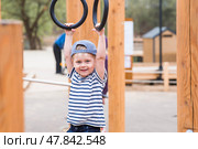 Lifestyle. A cute little boy is hanging on rings on a sports field in the fresh air. The concept of children's sports and physical development. Стоковое фото, фотограф Photojuli / Фотобанк Лори
