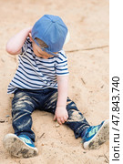 Summer lifestyle. A cute little boy is having fun playing with sand on the beach in a modern playground. The concept of family entertainment and leisure. Стоковое фото, фотограф Photojuli / Фотобанк Лори