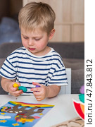 A little boy is playing with plasticine. Fine motor skills-developing games for children. The kid makes a horse. Useful games for child development. Стоковое фото, фотограф Photojuli / Фотобанк Лори