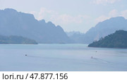 Panorama of the mountain above the water of Cheo Lan lake in Thailand during the day. View from the pier at Khao Sok Park on departing and arriving boats with tourists, traveling in Thailand. Стоковое видео, видеограф Владимир Разгуляев / Фотобанк Лори