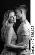 Beautiful couple in love hugging against black background. Studio black and white portrait photo of a girl blondes and a guy with short hair. Valentine's day. Loving married couple. Стоковое AI-изображение, AI-художник Sergey Grishin / Фотобанк Лори