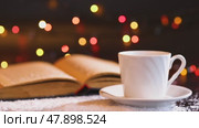White cup and saucer and an old open book on a dark wooden table covered with snow. Стоковое видео, видеограф Zakharova Natasha / Фотобанк Лори