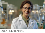 A scientist smiles in a laboratory, showcasing her enthusiasm for research amidst various scientific equipment. Стоковое AI-изображение, AI-художник Данила Большаков / Фотобанк Лори